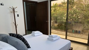 Un dormitorio con una cama grande, un perchero y vistas al exterior por una puerta corrediza.