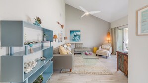 Una sala de estar moderna con un sofá seccional gris, un estante azul y un ventilador de techo.