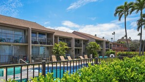Un hotel con piscina, varios balcones y palmeras.