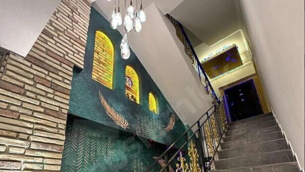 Una escalera con un muro decorativo de ladrillo y detalles dorados.