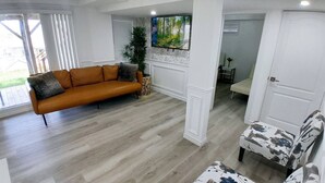A living room with a sofa, a chair, a TV, and a plant.