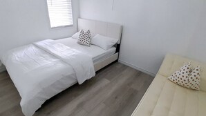 A bedroom with a bed, a nightstand, and a sofa.