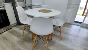 A modern kitchen with a round white table and four white chairs with wooden legs.