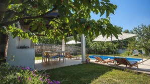 Ein Poolbereich mit Liegestühlen, einem Tisch und Sonnenschirmen.