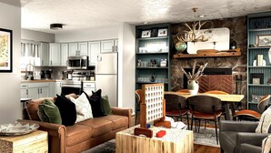 Ein modernes Wohnzimmer mit einer braunen Ledersofa, einem Holztisch und einem Essbereich mit Kamin aus Stein.