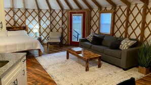 A cozy interior with a bed, sofa, and wooden coffee table. - Gray Yurt in Hocking (Logan)