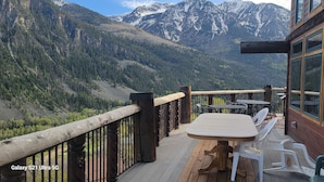 A wooden deck with a table and chairs, overlooking a mountainous landscape. - Amazing Mountain Getaway (Marble)