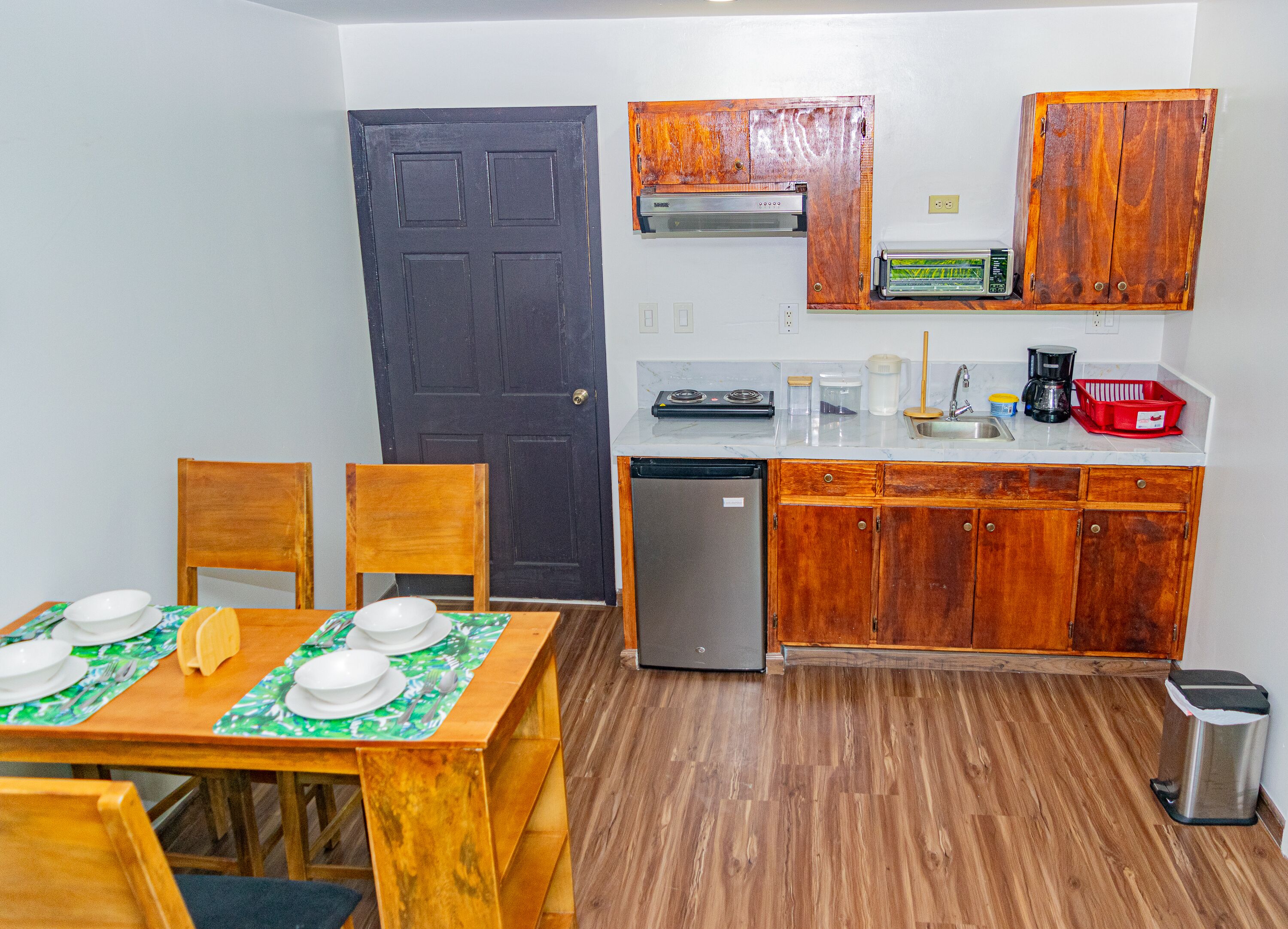 A compact kitchen with wooden cabinets, a built-in microwave, and a small refrigerator.