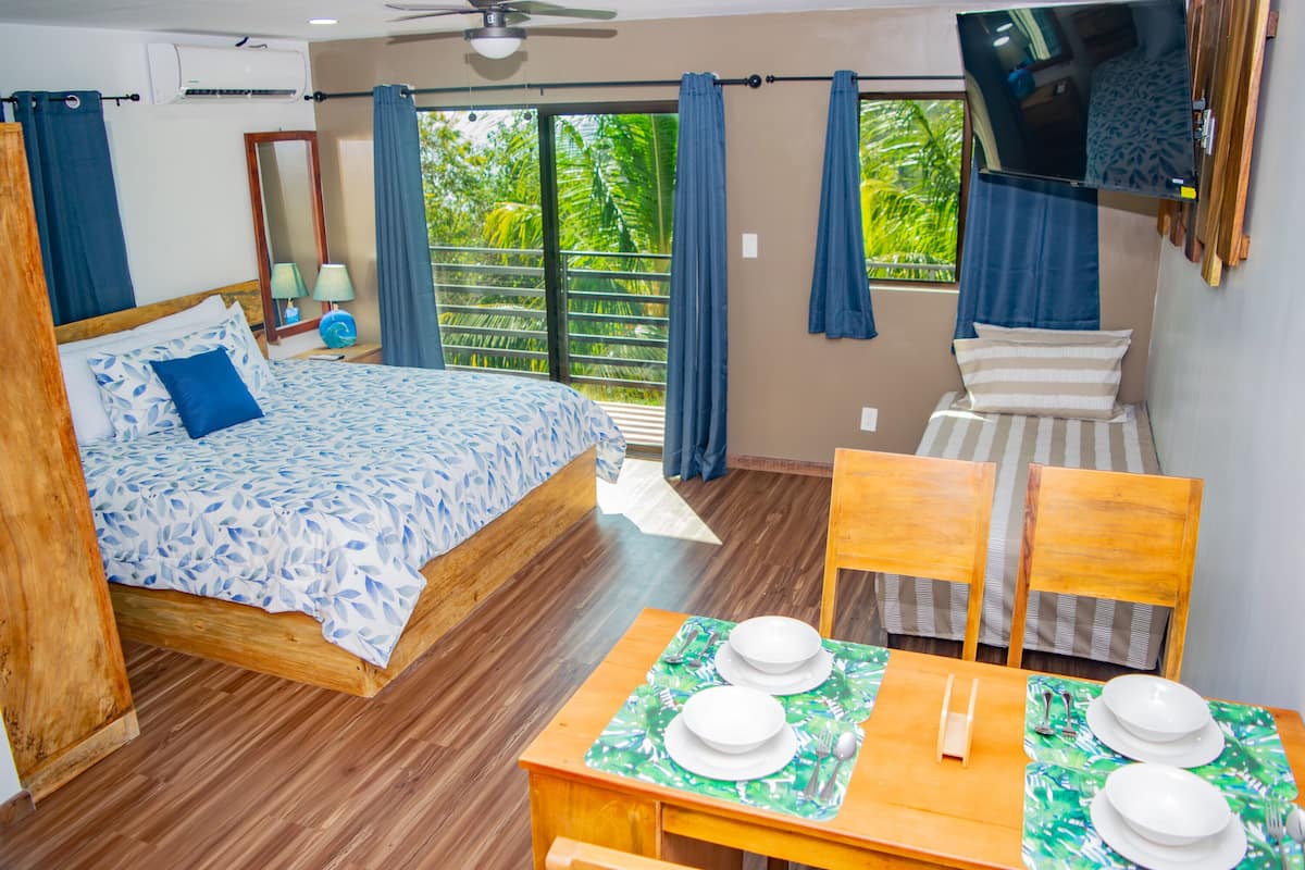 A bedroom with a bed, a table set for two, and a TV mounted on the wall.