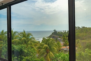 A view through a window of a tropical beach with palm trees and a clear sky. - Buena Vista El Zonte (Chiltiupan)