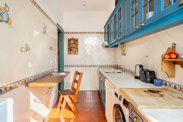 Una cocina funcional con una mesa de madera, una lavadora y un lavamanos.