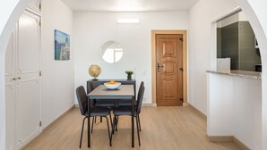 A compact kitchen with a dining table, chairs, a globe, and a bowl of fruit.