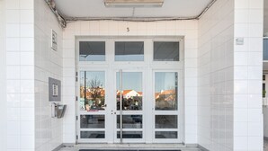 A building entrance with a tiled facade, a set of double doors, and a small sign above the door.