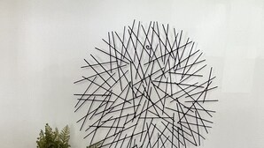 Una consola blanca con elementos decorativos, como una escultura geométrica, un adorno con forma de corazón y una planta en maceta.