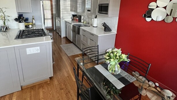 Una cocina moderna con comedor, que incluye una mesa de vidrio, sillas de madera y una pared de acento roja.
