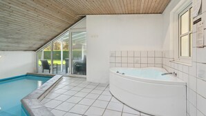 Un baño moderno con una bañera independiente, zona de ducha con mampara de vidrio y piscina.