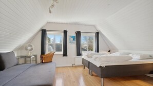 Un dormitorio con cama, sofá, sillón, ventana y ventilador de techo.