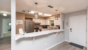 Una cucina moderna con mobili bianchi, elettrodomestici in acciaio inossidabile e luci a sospensione.