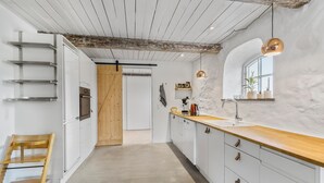 Une cuisine moderne avec des meubles blancs, un plan de travail en bois et un plafond rustique.