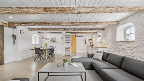 Un salon spacieux avec un canapé gris, une table basse et un coin repas comprenant des chaises et une table en bois.
