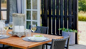 Une table en bois, mise avec des verres à vin, une carafe et un saladier rempli de salade.