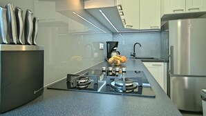 Eine moderne Küche mit einem Gasherd, einer Kaffeemaschine und einem Edelstahl-Kühlschrank.