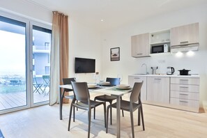 A modern kitchen with a dining area, a TV, and a view of the city.