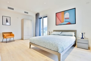 A modern bedroom with a bed, a nightstand, a wardrobe, and a window with curtains.