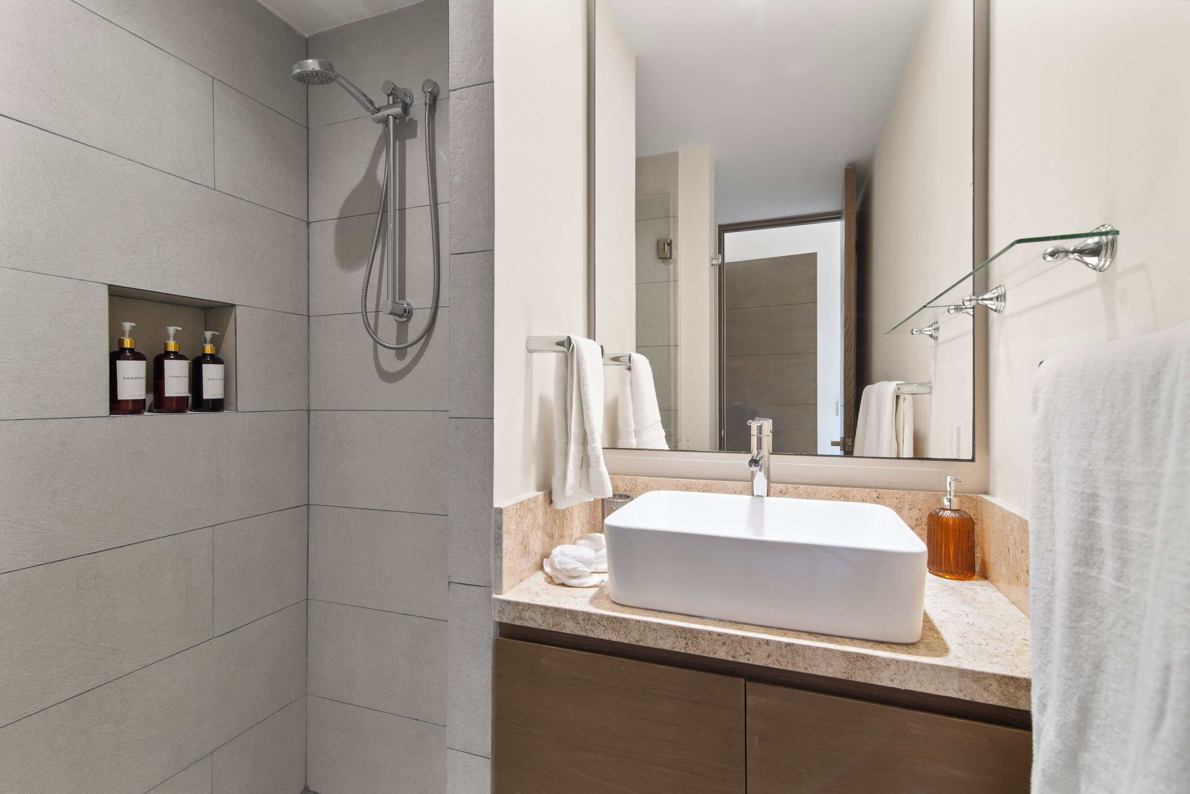 Un baño moderno con un espejo grande, un lavabo blanco y una zona de ducha.