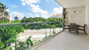 Un balcone con un set da pranzo e vista sulla spiaggia e sul verde.