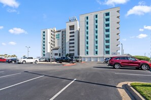 Un hotel de varios pisos con un estacionamiento al frente.