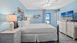 Ein Schlafzimmer mit Bett, Nachttisch, Kommode und Deckenventilator.