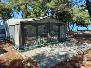 Une tente de camping dotée d’une entrée abritée, d’un espace de couchage et offrant une vue sur l’eau.