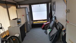 Una habitación funcional y compacta con kitchenette, una bicicleta y un ventanal que proporciona luz natural.