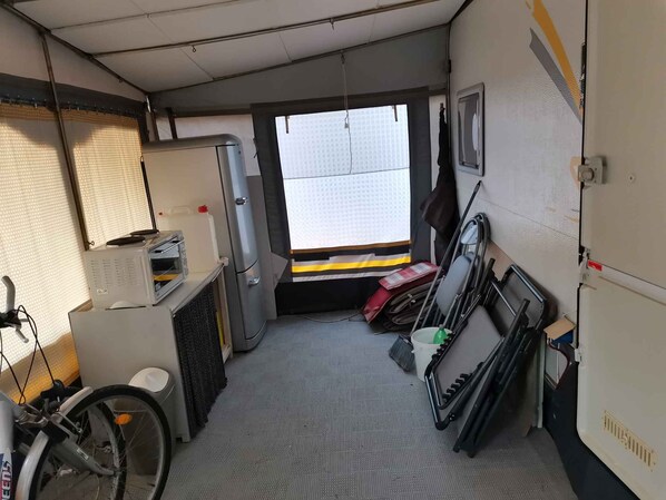 A compact, utilitarian room with a kitchenette, a bicycle, and a window providing natural light.