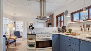 A modern kitchen with a white stove, blue cabinets, and a large window.
