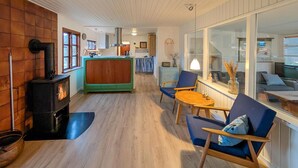 A cozy living room with a wood-burning stove, a green sofa, and blue chairs.