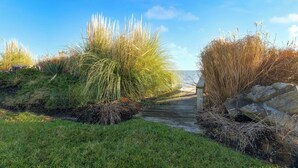 A pathway leading to a wooden structure surrounded by tall grasses and rocks. - Bay Cottage by Avantstay Waterfront, Pier, Pond (Dameron)