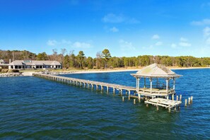 A waterfront property with a long pier leading to a gazebo and a house with a large roof and multiple windows. - Bay Cottage by Avantstay Waterfront, Pier, Pond (Dameron)
