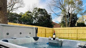 A hot tub with a wooden fence in the background.