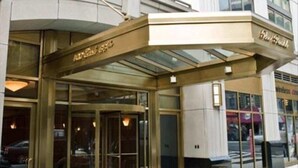 A hotel entrance with a glass door and a curved awning. - Walk to Central Park! Cozy 1BR w. AC, Wifi & Heating (New York)
