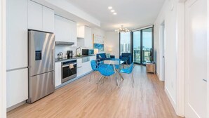 A modern kitchen with white cabinets, a stainless steel refrigerator, and a dining area with blue chairs. - Close to Resturants, Parks& Museums | Park West | Miami (Miami)