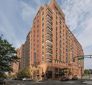 A high-rise building with a modern architectural design, featuring a prominent corner entrance and multiple floors with uniform window patterns.