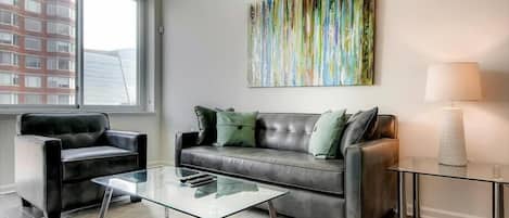 Una sala de estar moderna con un sofá de cuero, una mesa de centro de vidrio y un cuadro en la pared.