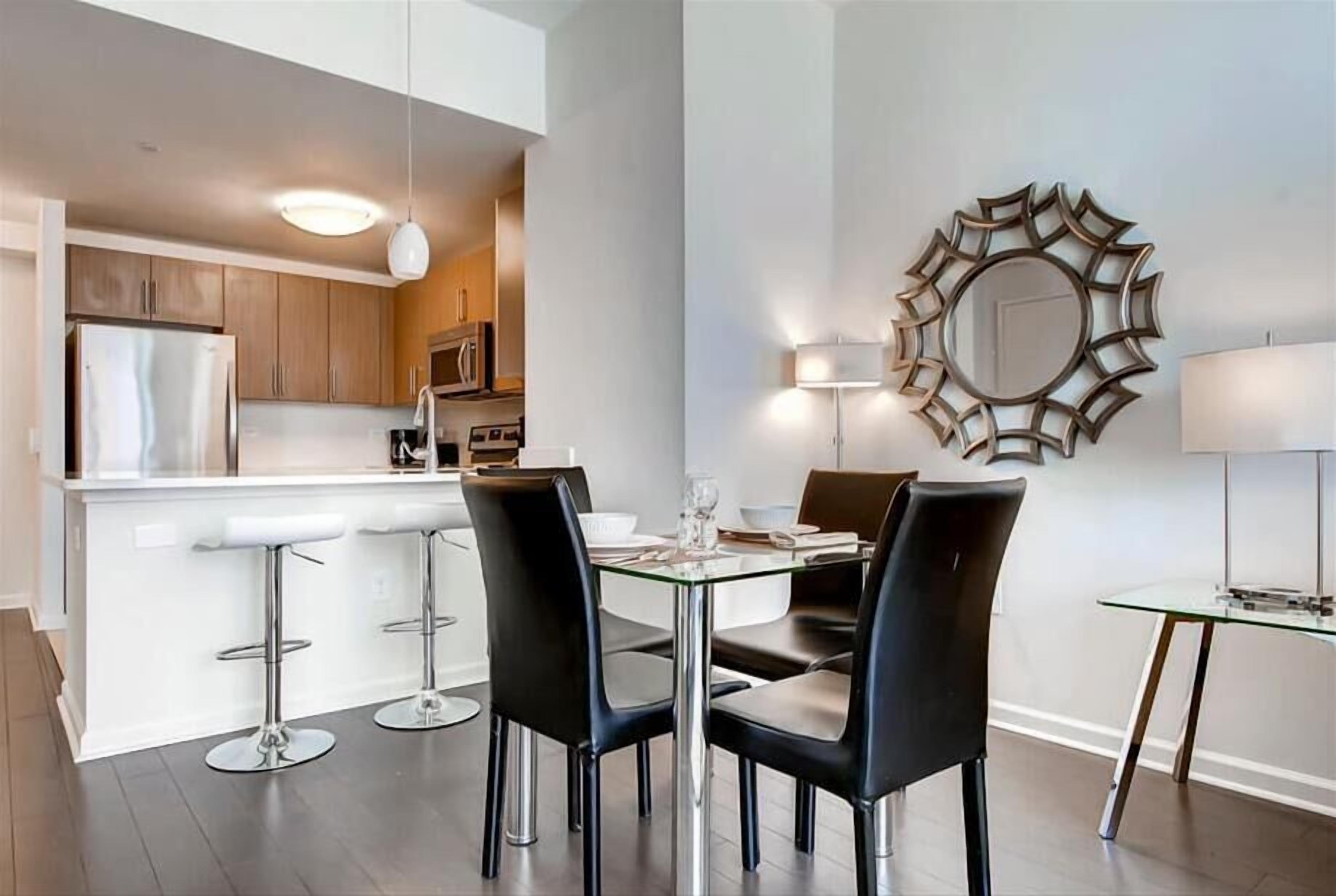 Una cocina moderna con una isla central, taburetes de bar y una mesa de comedor con sillas.