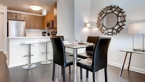 A modern kitchen with a central island, bar stools, and a dining table with chairs. - Modern Jersey City 1BR | Work Desk + Wi-Fi | by GLS (Jersey City)