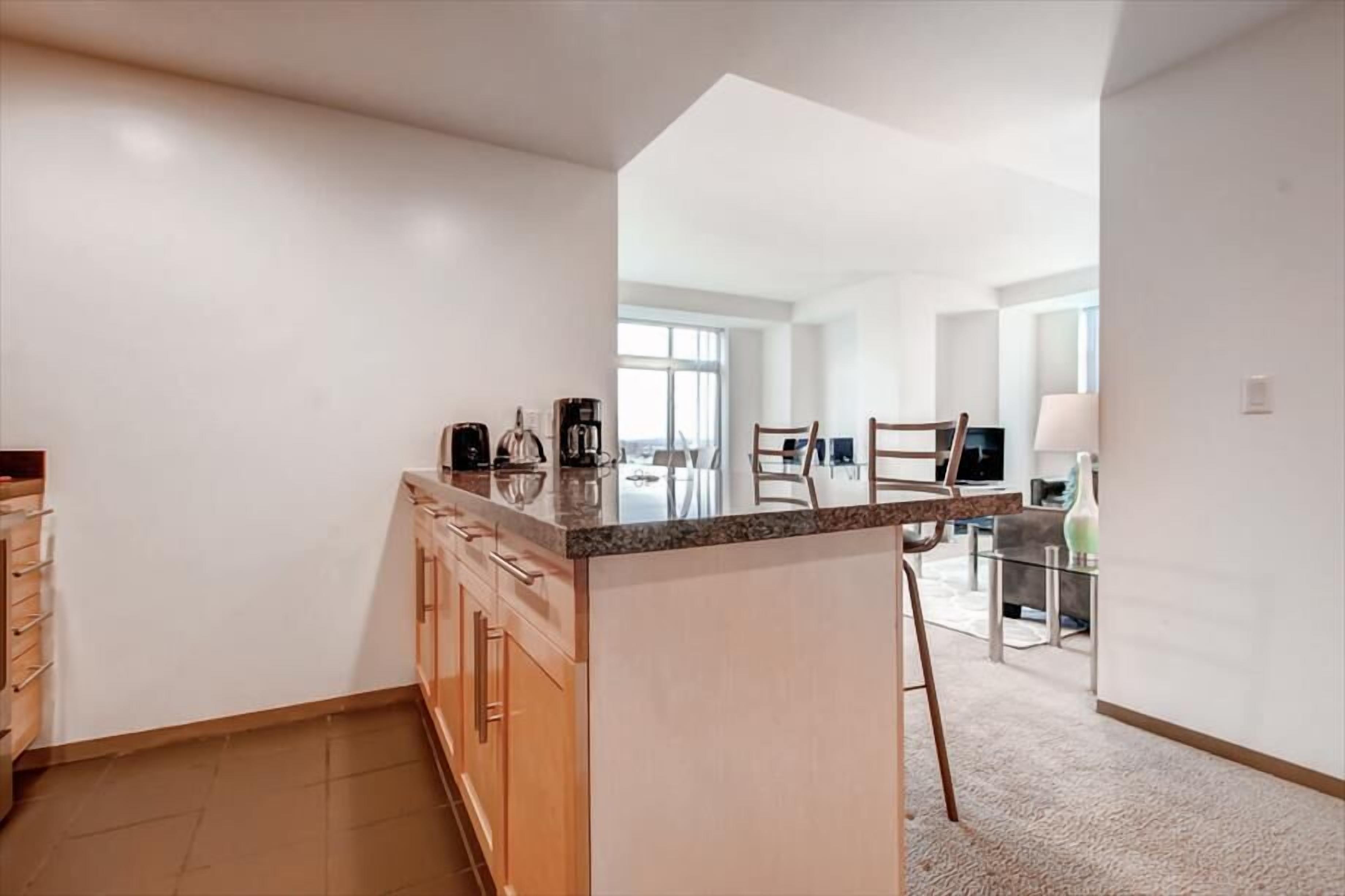A modern kitchen with a central island, wooden cabinets, and a view into the dining area.