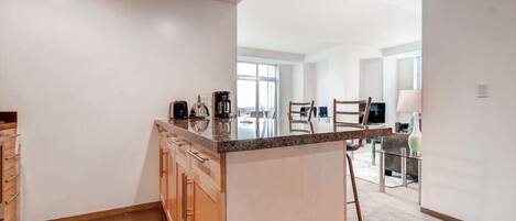A modern kitchen with a central island, wooden cabinets, and a view into the dining area.