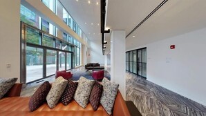 Um espaço amplo e interno, com janelas grandes, área de estar com almofadas e parede com padrão.