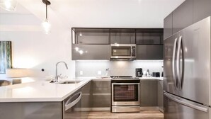 Uma cozinha moderna com eletrodomésticos de aço inoxidável, uma ilha central e um forno embutido.